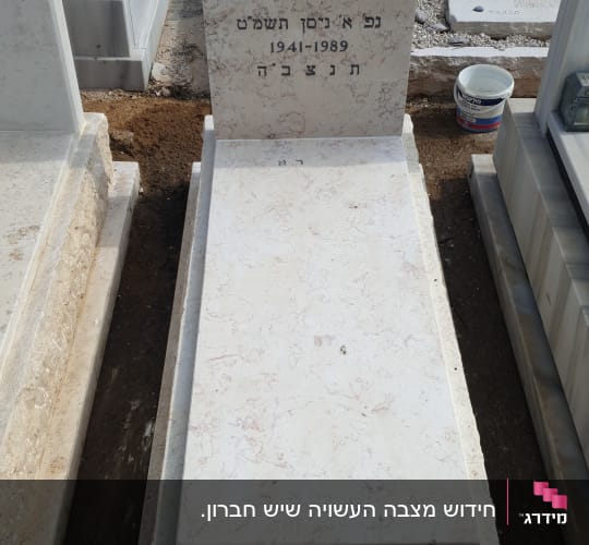 מצבה לבנה עם כיתוב בעברית בבית קברות